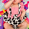 baby, child, infant, pink_clothing, bow, play_mat, colorful, rainbow, butterfly, sitting, cute, white_shoes, bracelet, face, hand, funny_gesture, patterned_clothing, indoor, happy, young
