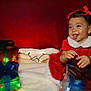 toddler, child, girl, red_dress, holiday, christmas, presents, gift_boxes, lights, smile, tongue_out, cute, festive, celebration, happy, indoors, portrait, holiday_decor, holiday_lights, soft_blanket