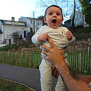 Vardan a rejoint le concours — aidez-le/la à gagner de superbes lots ! baby, infant, child, smiling, surprised, adult_hand, tattoo, wedding_ring, white_clothing, socks, outdoors, house, fence, grass, pathway, trees, sky, portrait, happy, holding