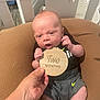 Finnick is registered to the contest to win money with this photo: baby, infant, two_months, cushion, brown, hand, wooden_sign, shorts, black_shirt, mohawk_hairstyle, indoor, person, newborn, cute, sitting, soft_lighting, home, portrait, skin, expression