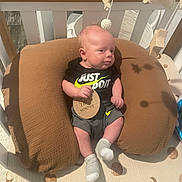 Finnick is registered to the contest to win money with this photo: baby, infant, crib, cushion, clothing, socks, sign, text, wood, nursery, mobile, star, person, indoor, soft_toys, brown, white, cute, child, sleeping_area