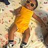 Enzo joined the competition — help win amazing prizes! accessory, baby, blanket, casual, child, cute, fashion, floral_pattern, funny, indoor, infant, lying_down, person, portrait, relaxed, sleepwear, socks, sunglasses, toddler, yellow_onesie