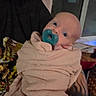River is registered to the contest to win money with this photo: baby, infant, child, portrait, pacifier, blanket, wrapped, bundled, held, adult, face, eyes, indoors, window, home, cozy, clothing, sitting, close_up, photography