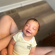 Milanie joined the competition — help win amazing prizes! baby, child, smiling, onesie, hello_kitty, yellow_stripes, sitting, indoor, floor, legs, happy, infant, person, cute, skin, head, hand, portrait, relaxed, closed_eyes