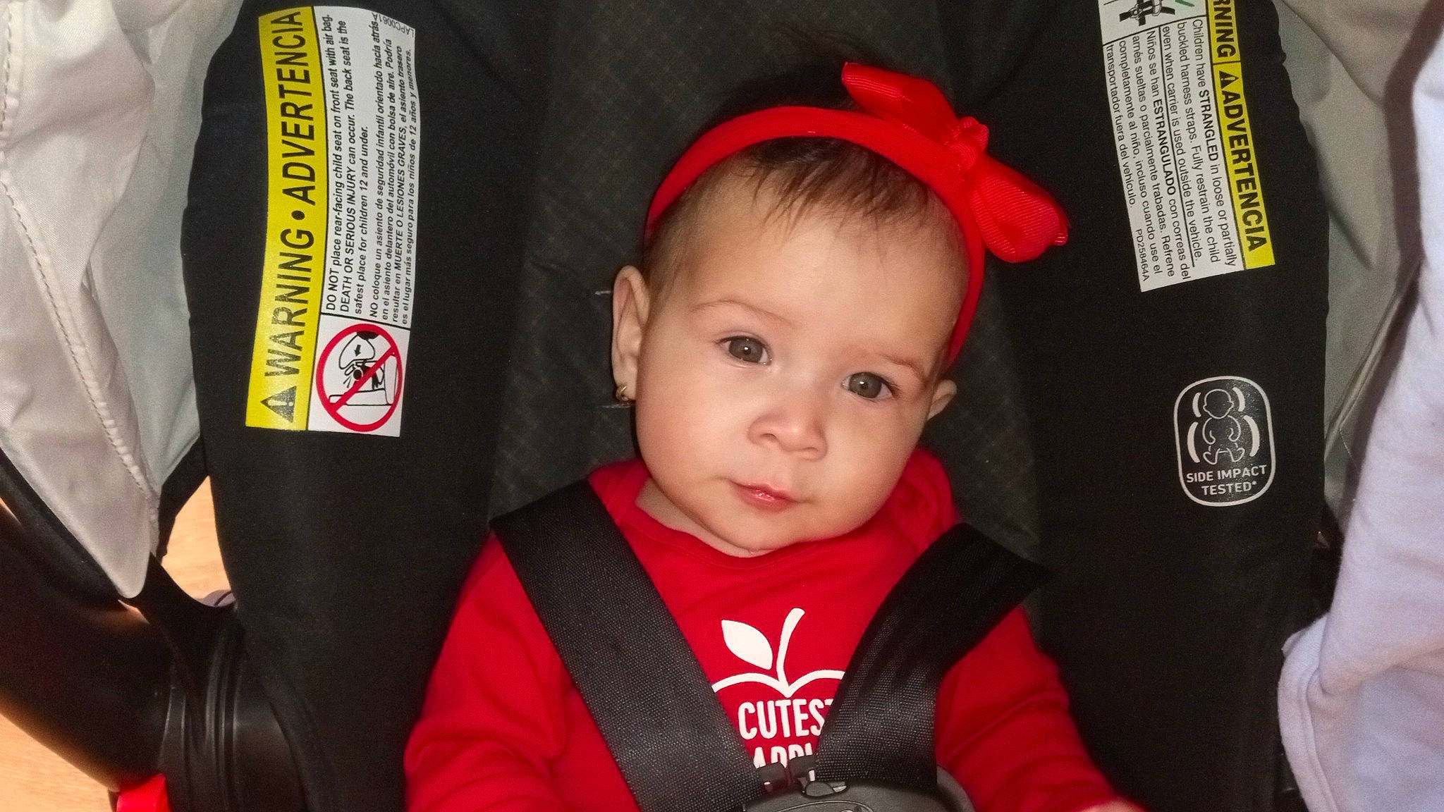 Estrella is registered to the contest to win money with this photo: baby, baby_toddler_clothing, black, cap, carmine, child, costume_hat, event, fashion_accessory, fun, happy, hat, person, personal_protective_equipment, red, sitting, sleeve, toddler, tradition, uniform