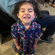 Nazly joined the competition — help win amazing prizes! background_people, bracelet, candid, carpet, casual_clothing, child, colorful_socks, earrings, floral_dress, footwear, girl, happy, indoor, messy_hair, person, phone, portrait, seated_adult, smiling, standing