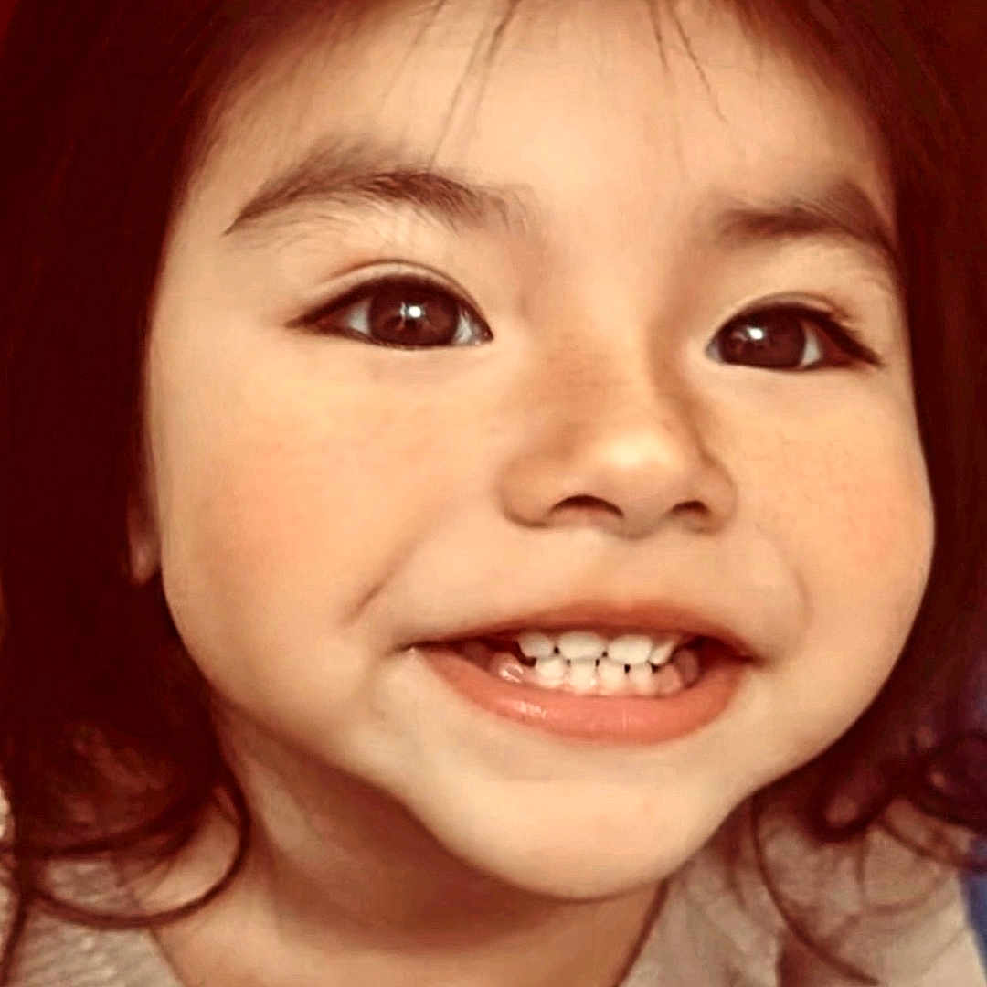 Nazly is registered to the contest to win money with this photo: baby_teeth, cheeks, child, closeup, cute, dark_hair, eyebrows, eyes, face, happy, indoor, looking_up, mouth, person, portrait, skin, smiling, sweater, warm_lighting, young