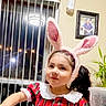 Nazly joined the competition — help win amazing prizes! bunny_ears, child, collar, cup, cute, face, framed_photo, girl, hair, indoor, lighting, pigtails, plaid_dress, plant, playful, portrait, smile, table, vertical_blinds, window