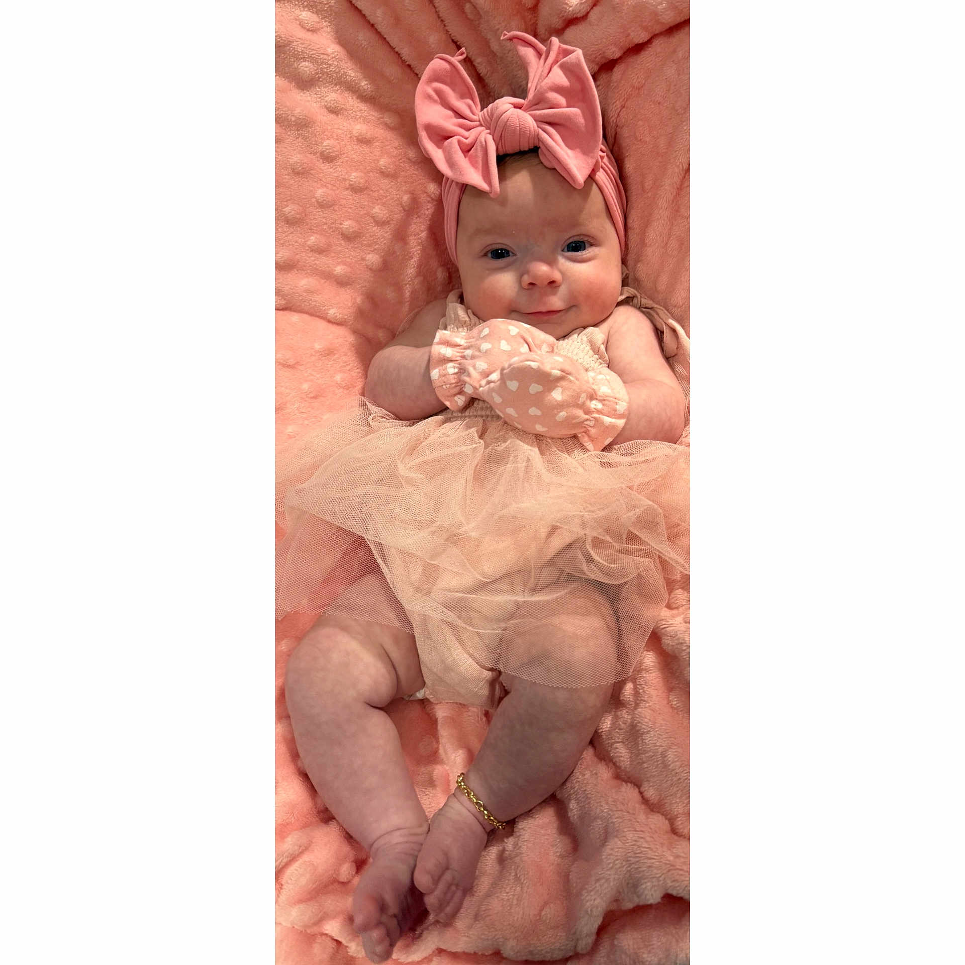 Hailey is registered to the contest to win money with this photo: baby, infant, pink, tutu, headband, bow, blanket, soft_texture, smile, cute, lying_down, bracelet, clothing, hands, feet, portrait, child, adorable, happy, cozy
