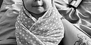 Hailey is registered to the contest to win money with this photo: baby, infant, polka_dot, blanket, headband, bow, smile, face, tattoo, arm, black_and_white, portrait, cute, wrapped, bed, fabric, person, newborn, resting, soft