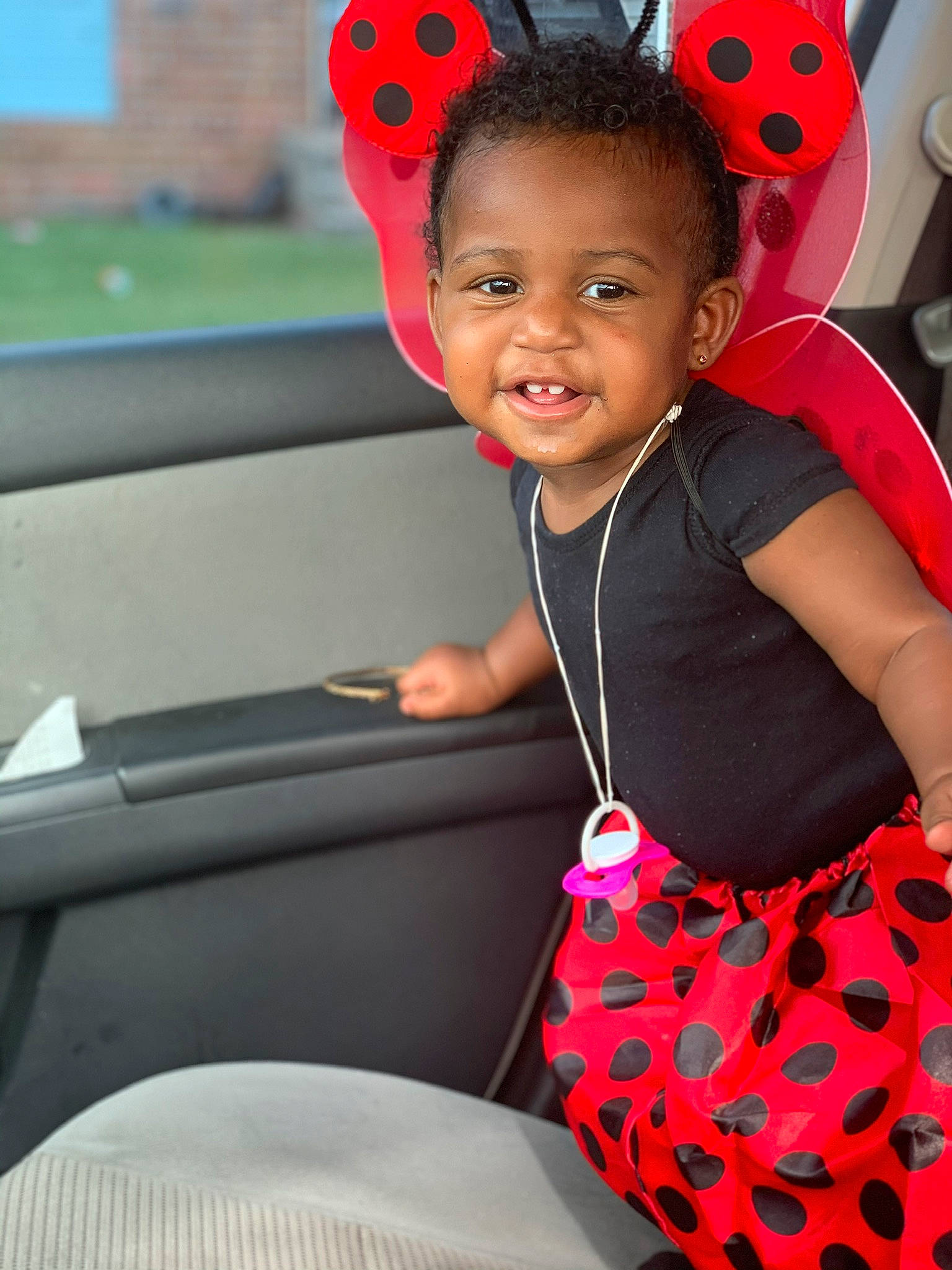 Zyla is registered to the contest to win money with this photo: auto_part, baby, car, car_seat, child, costume, design, ear, happy, headgear, joy, leisure, pattern, person, pink, plant, red, smile, steering_wheel, toddler
