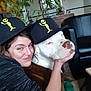 affection, animal, black_leather_chair, cap, casual, decor, dog, face, friendship, furniture, hat, home, indoor, person, pet, plant, portrait, relaxed, smile, woman