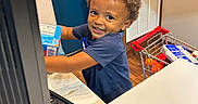 Amarion joined the competition — help win amazing prizes! blue_shirt, blue_wall, cash_register, child, counter, curly_hair, fun, groceries, happy, indoor, keyboard, kid, person, play, pretend, retail, sign, smiling, store, toy_shopping_cart