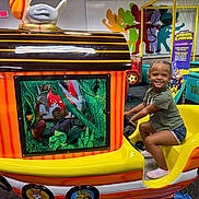 Arabella joined the competition — help win amazing prizes! child, smiling, braided_hair, indoor, playground, ride, train, colorful, toy, fun, happy, person, play_area, trampoline, wall_art, entertainment, casual_clothing, childrens_play, shoe, seat