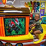 child, smiling, braided_hair, indoor, playground, ride, train, colorful, toy, fun, happy, person, play_area, trampoline, wall_art, entertainment, casual_clothing, childrens_play, shoe, seat