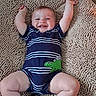 baby, infant, child, smiling, happy, lying_down, arms_raised, portrait, striped_outfit, navy_clothing, crocodile_design, green_crocodile, textured_rug, indoor, close_up, face, eyes, mouth, bare_legs, socks