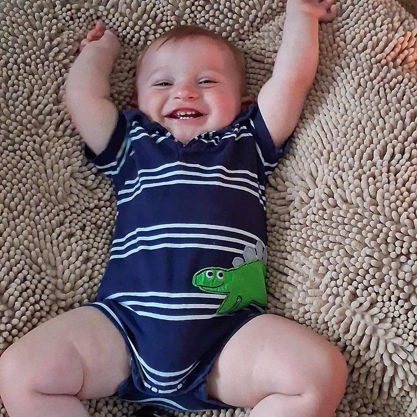 Jack joined the competition — help win amazing prizes! baby, infant, child, smiling, happy, lying_down, arms_raised, portrait, striped_outfit, navy_clothing, crocodile_design, green_crocodile, textured_rug, indoor, close_up, face, eyes, mouth, bare_legs, socks