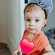 Alexandra a rejoint le concours — aidez-le/la à gagner de superbes lots ! toddler, child, headband, 2026, orange_shirt, hand, face, eyes, indoor, soft_texture, curious, person, young_child, baby, portrait, cute, light, expression, skin, hair