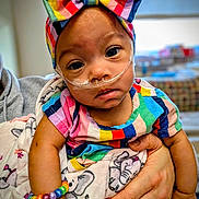 Sirene joined the competition — help win amazing prizes! baby, child, infant, bow, rainbow, bracelet, nasal_cannula, colorful_clothing, hand, person, portrait, closeup, cute, hospital, medical_device, smiling, baby_blanket, elephant_pattern, indoor, holding