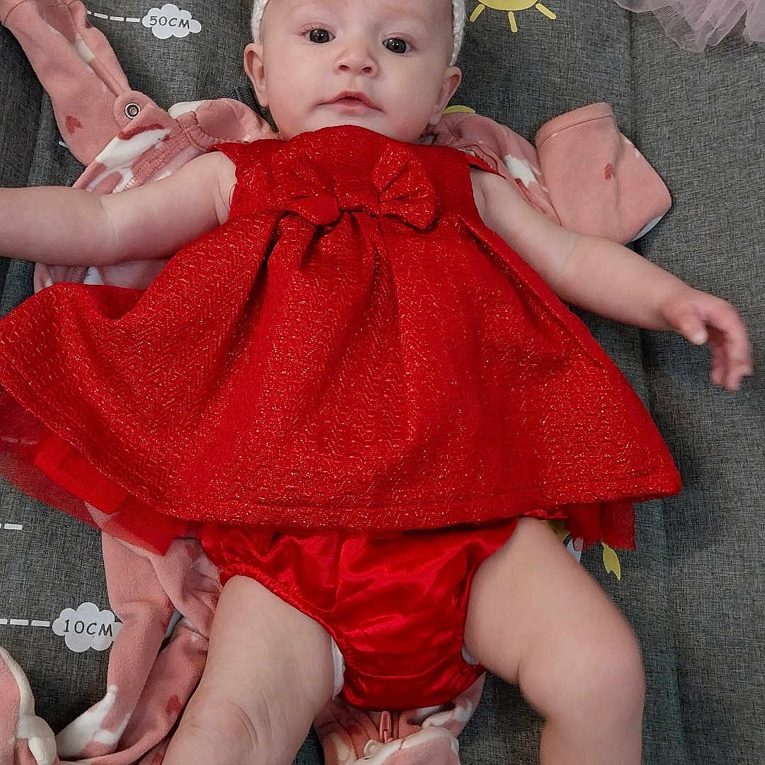 Delta joined the competition — help win amazing prizes! baby, blanket, child, clothing, couch, cute, fabric, face, floor, headband, indoor, infant, person, pink, portrait, red_dress, socks, stuffed_animals, toy, white