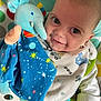 baby, child, plush_toy, elephant, smile, cute, infant, baby_bib, colorful, patterned, seat, happy, indoors, soft_toy, closeup, young, person, clothing, portrait, hand