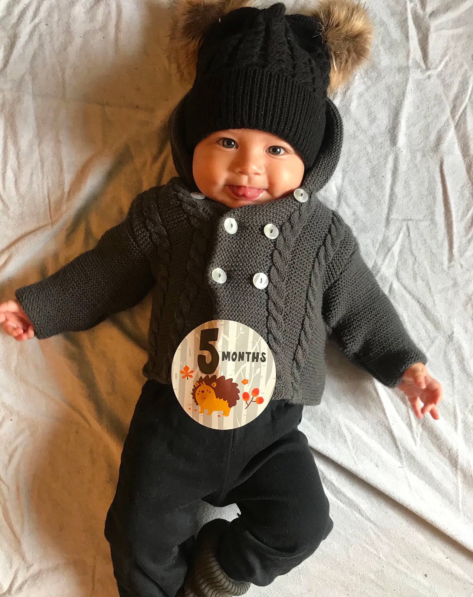 Logan a rejoint le concours — aidez-le/la à gagner de superbes lots ! baby, baby_products, baby_toddler_clothing, cap, child, clothing, comfort, face, facial_expression, headgear, headwear, jacket, knit_cap, linens, outerwear, person, sleeve, smile, textile, toddler