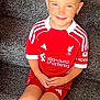 Taylor is registered to the contest to win money with this photo: child, smiling, red_clothing, sportswear, football_kit, sitting, carpet, stairs, bow, hair_accessory, white_shoes, sock, happy, portrait, indoors, cute, young, european, kid, sporty