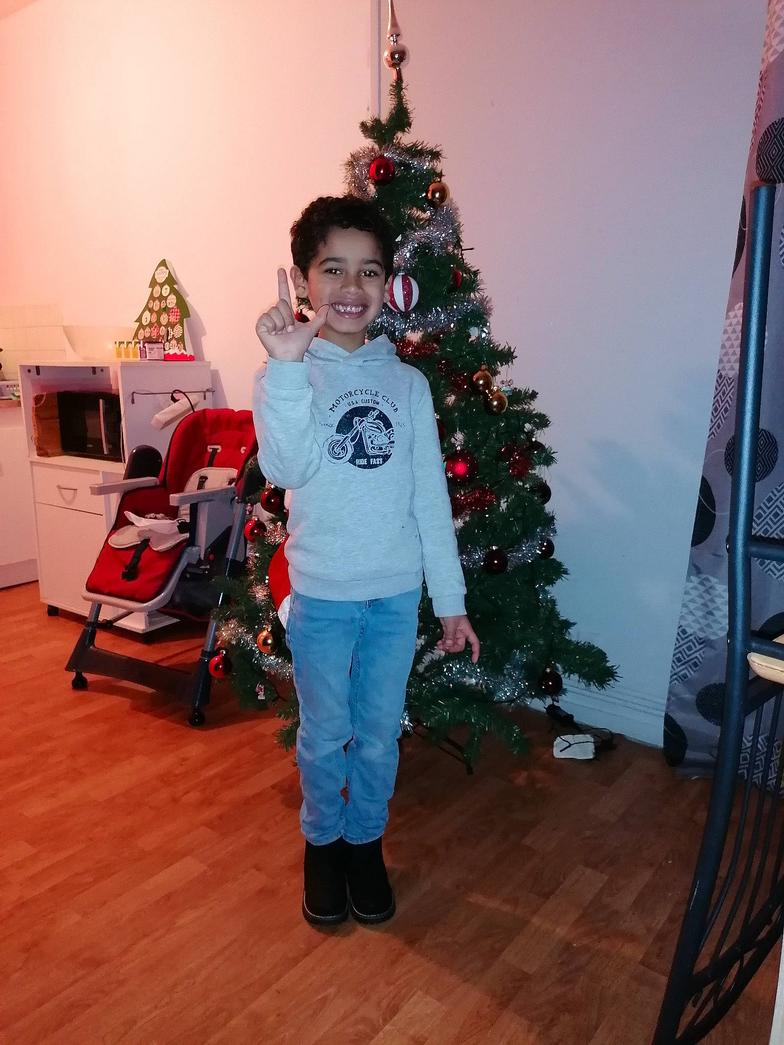 Austin participe au concours pour gagner de l'argent avec cette photo : christmas, christmas_decoration, christmas_eve, christmas_ornament, christmas_tree, conifer, event, evergreen, flooring, fun, hardwood, holiday, holiday_ornament, joy, lap, ornament, person, room, smile, toddler