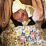 baby, sleeping, bow, headband, blanket, floral_pattern, car_seat, pink, infant, child, closeup, face, peaceful, resting, indoors, soft_lighting, cute, clothing, newborn, toddler