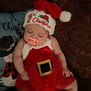 Kinsley joined the competition — help win amazing prizes! baby, child, christmas_hat, couch, cozy, cute, decor, face, festive, holiday, indoors, infant, pacifier, pillow, red_dress, resting, seasonal, sleeping, socks, soft_lighting