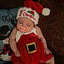 baby, child, christmas_hat, couch, cozy, cute, decor, face, festive, holiday, indoors, infant, pacifier, pillow, red_dress, resting, seasonal, sleeping, socks, soft_lighting