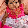 baby, infant, child, pink_dress, traditional_clothing, curly_hair, bracelet, lying_down, fabric, peach_color, gold_embroidery, portrait, cute, small_hands, foot, indoors, expression, young_child, head_accessory, person