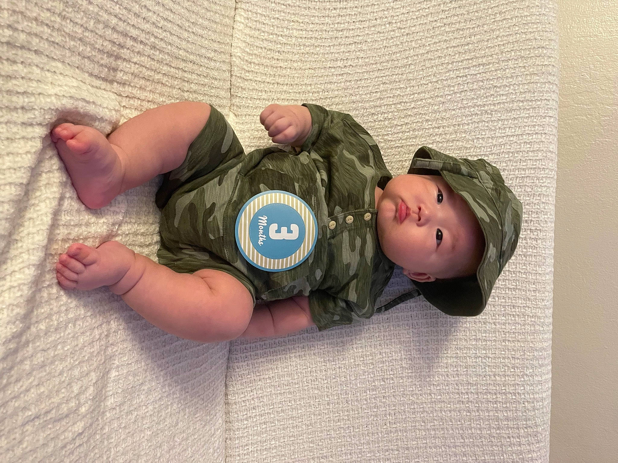 Iveel is registered to the contest to win money with this photo: baby, baby_toddler_clothing, camouflage, cap, child, fashion_accessory, finger, fun, gesture, headgear, headwear, pattern, person, personal_protective_equipment, skin, sleeve, thumb, toddler, toy, wood