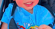 Lyndon is registered to the contest to win money with this photo: baby, birthday_sticker, blue_shirt, cap, child, clothing, colorful, daylight, face, hand, happy, outdoor, person, photography, portrait, seat, seatbelt, smile, stroller, toddler
