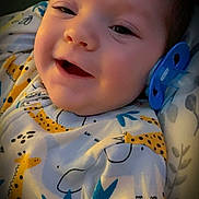 Bradley joined the competition — help win amazing prizes! baby, smiling, pacifier, onesie, giraffe_pattern, infant, face, closeup, cute, child, sleepwear, cozy, happy, portrait, indoor, young, person, soft_lighting, expression, resting