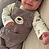 baby, smiling, corduroy, overalls, bear_face, infant, cute, child, happy, clothing, reaching_hand, lying_down, soft_surface, portrait, indoors, person, toddler, apparel, face, cute_outfit