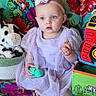 Athena is registered to the contest to win money with this photo: baby, child, purple_dress, headband, toy, plush_toy, colorful_blanket, indoor, sitting, barefoot, cute, blue_eyes, young_child, decor, soft_toys, playtime, floor_seating, expression, person, portrait