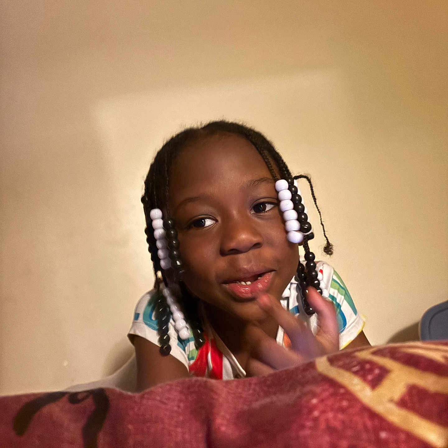 Kynnedi is registered to the contest to win money with this photo: child, girl, smile, beads, braids, bed, blanket, indoor, portrait, person, face, happy, casual, young, cute, pattern, clothing, furniture, resting, home