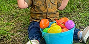 Anthony joined the competition — help win amazing prizes! toddler, child, grass, plastic_eggs, bucket, outdoor, fence, shirt, jeans, sneakers, toy, candy, play, happy, nature, spring, easter, curious, sitting, daylight