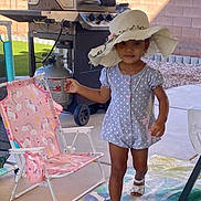 Layla joined the competition — help win amazing prizes! toddler, child, hat, polka_dot, romper, outdoor, patio, grill, chair, pink, unicorn, footwear, sandal, concrete, wall, grass, sunlight, smile, person, walking