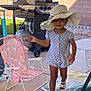 toddler, child, hat, polka_dot, romper, outdoor, patio, grill, chair, pink, unicorn, footwear, sandal, concrete, wall, grass, sunlight, smile, person, walking