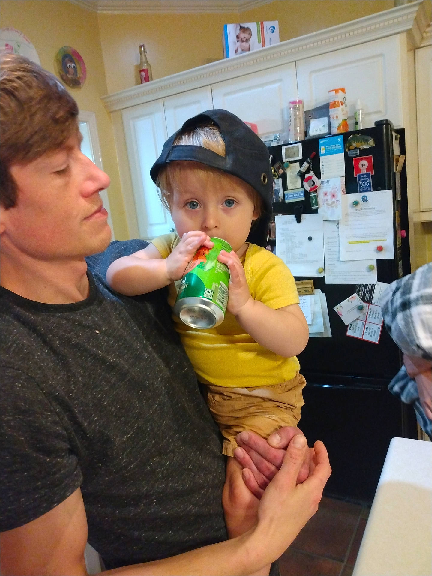 Elijah joined the competition — help win amazing prizes! adult, beverage, can, cap, casual, child, drink, family, holding, home, indoor, kitchen, magnet, notes, person, portrait, refrigerator, shorts, toddler, yellow_shirt