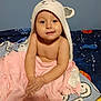 toddler, child, baby, towel, hooded_towel, bear_ears, bed, blanket, pink, blue, space_theme, smiley_faces, smiling, cute, portrait, indoor, person, skin, face, hands