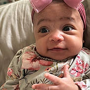 Bobby-Sage joined the competition — help win amazing prizes! baby, infant, pink_bow, floral_clothing, hand, face, eyes, expression, cute, portrait, child, person, indoors, soft_light, skin, headwear, sleeves, fabric, couch, closeup