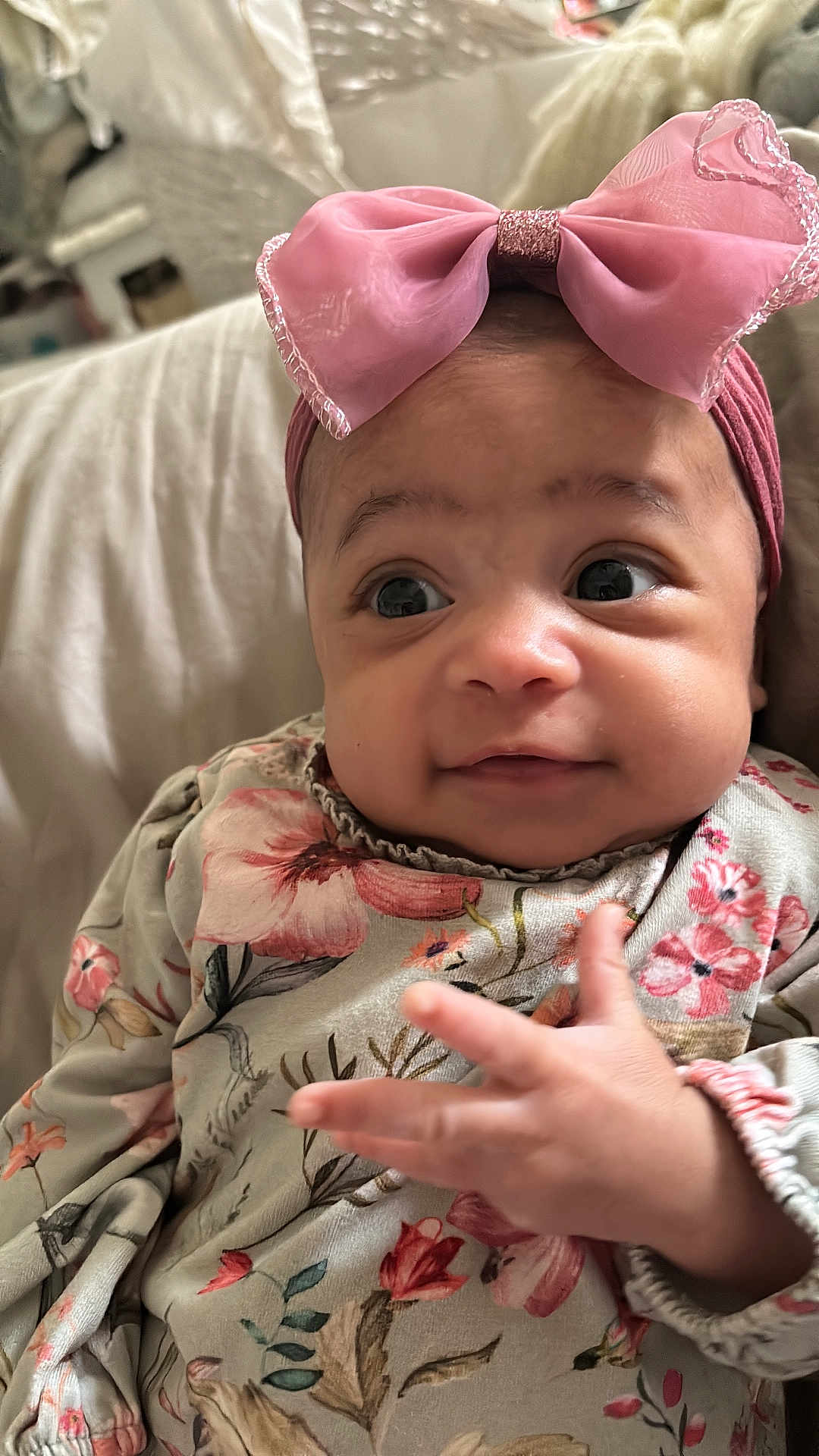 Bobby-Sage joined the competition — help win amazing prizes! baby, infant, pink_bow, floral_clothing, hand, face, eyes, expression, cute, portrait, child, person, indoors, soft_light, skin, headwear, sleeves, fabric, couch, closeup