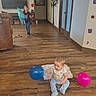 Asher joined the competition — help win amazing prizes! baby, child, children, balloons, birthday, indoor, living_room, wooden_floor, blanket, seated, standing, stuffed_animal, television, couch, home, family, portrait, playful, celebration, colorful