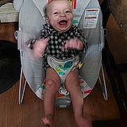 Asher is registered to the contest to win money with this photo: baby, infant, child, smiling, laughing, sitting, bouncer, baby_seat, indoor, portrait, plaid_shirt, diaper, toy, colorful, wooden_floor, happy, face, arms, legs, home