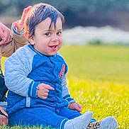 Riyansh joined the competition — help win amazing prizes! toddler, child, grass, blue_clothing, smile, outdoor, person, sitting, happy, casual_wear, daylight, portrait, young_child, jacket, shoes, sock, hand, support, nature, greenery