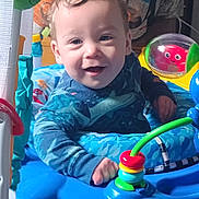 Jaseh is registered to the contest to win money with this photo: baby, child, smiling, curly_hair, blue, toy, activity_center, indoor, playful, colorful, happy, person, infant, cute, face, hand, clothing, seat, bright, fun