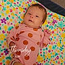 baby, infant, onesie, polka_dots, blanket, floral_pattern, lying_down, cute, child, newborn, face, skin, hand, leg, indoors, soft_light, colorful, cozy, portrait, sleepwear